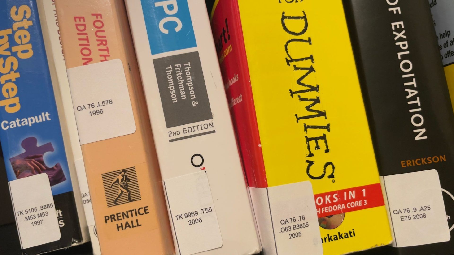 5 books sitting on a bookshelf, each with stickers on their spines showing a Library of Congress Classification number
