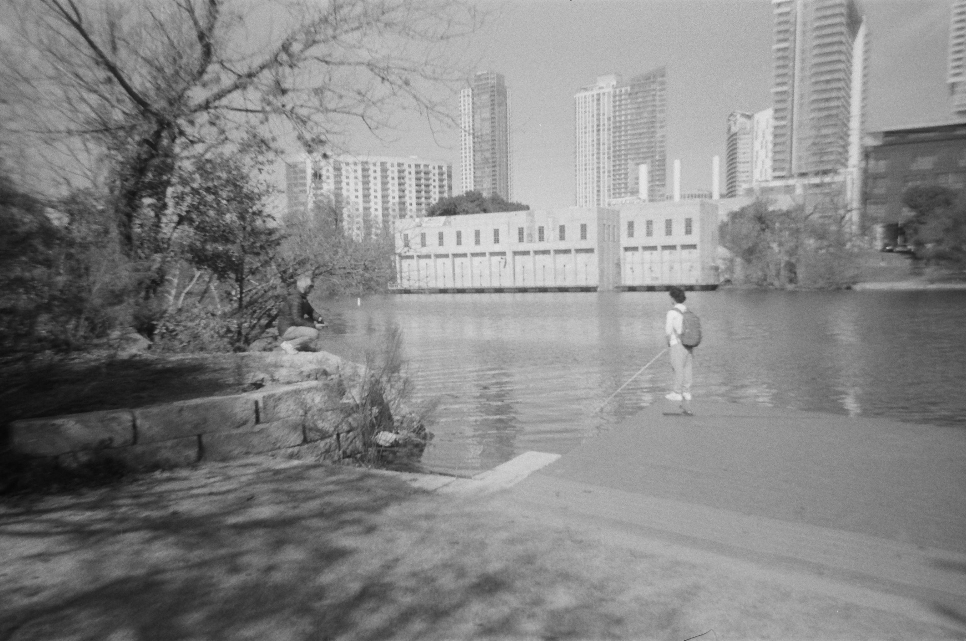 A kid learning to fish on Town Lake, with the Austin skyline in the background
