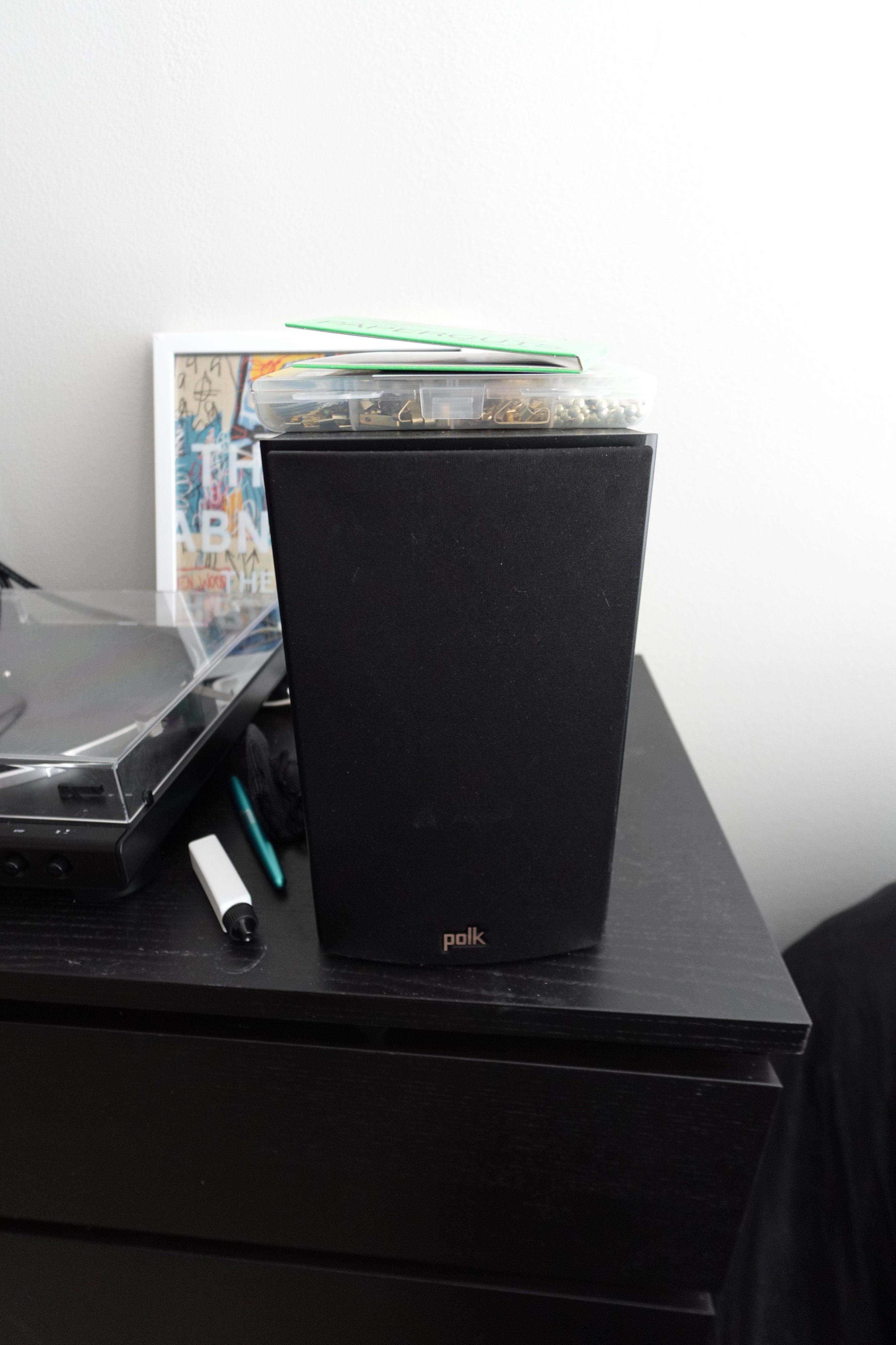 One of my Polk T15 speakers as seen from the front, with a bunch of clutter all around it.
