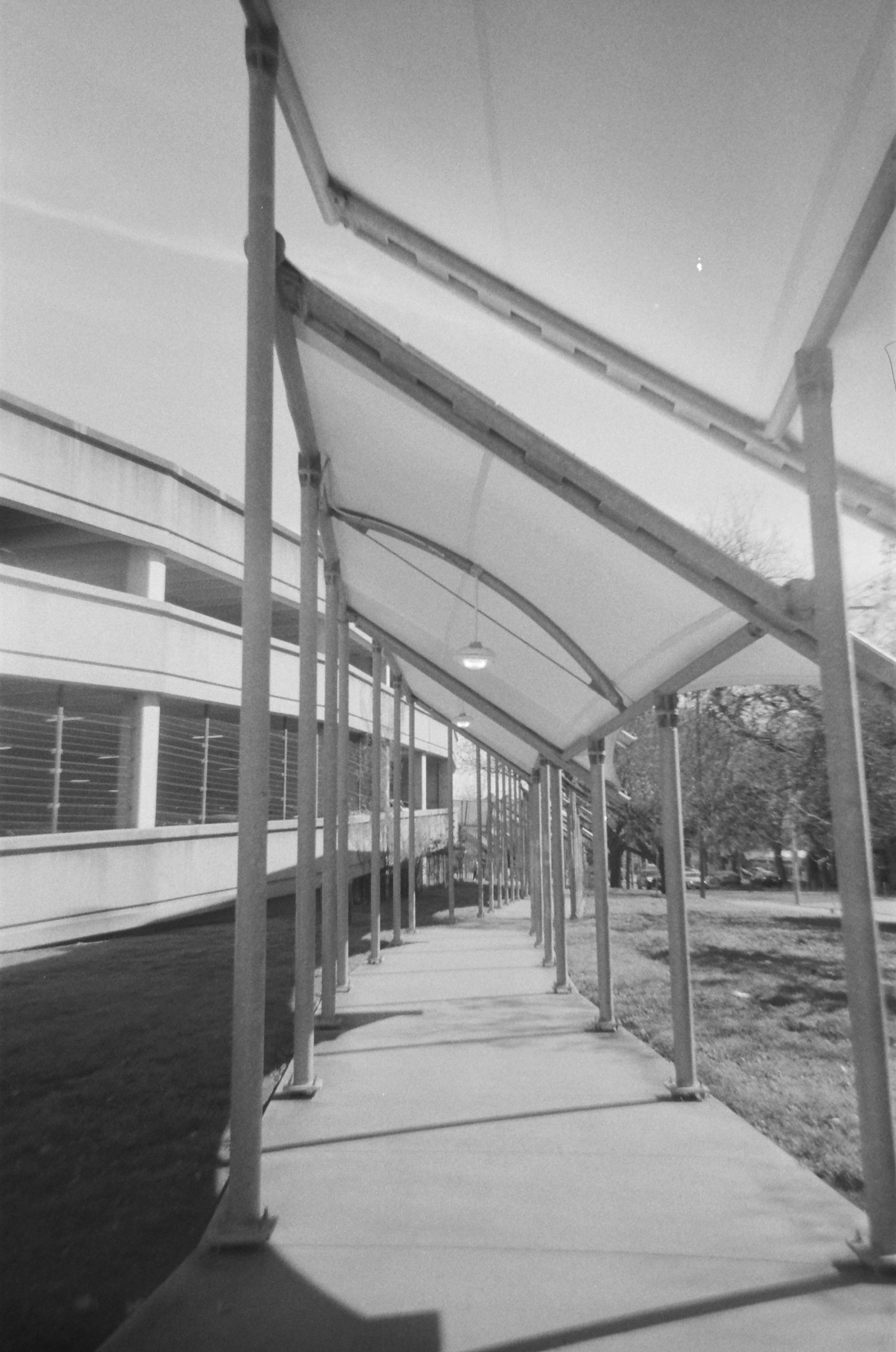 A covered sidewalk next to a parking garage