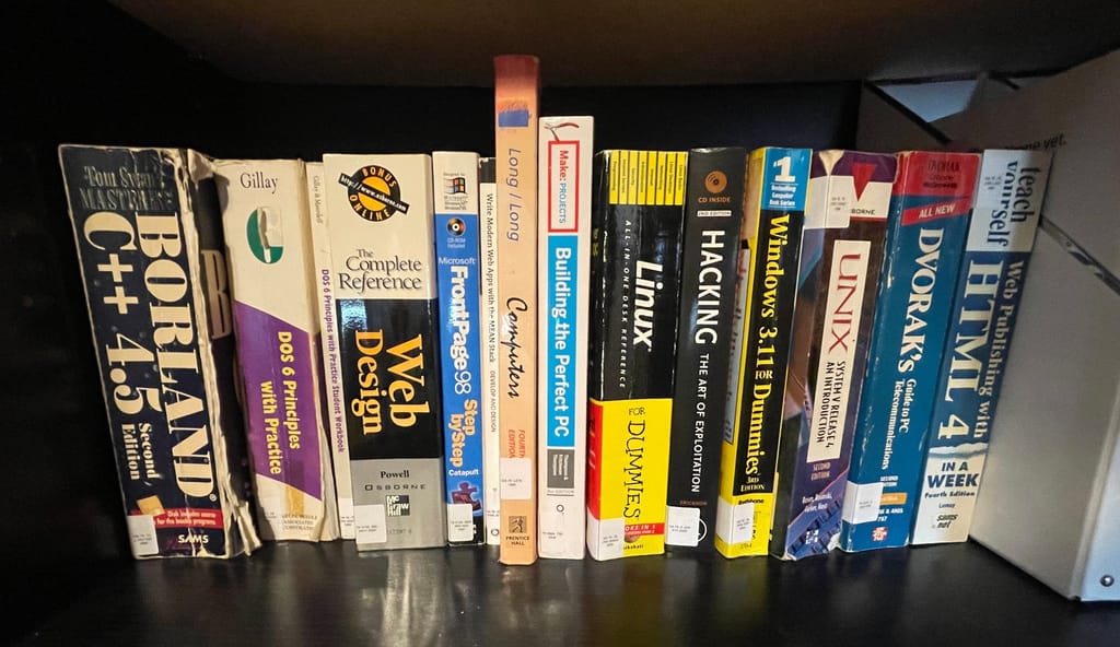 14 books sitting on a bookshelf, each labelled with a call number label as described above.