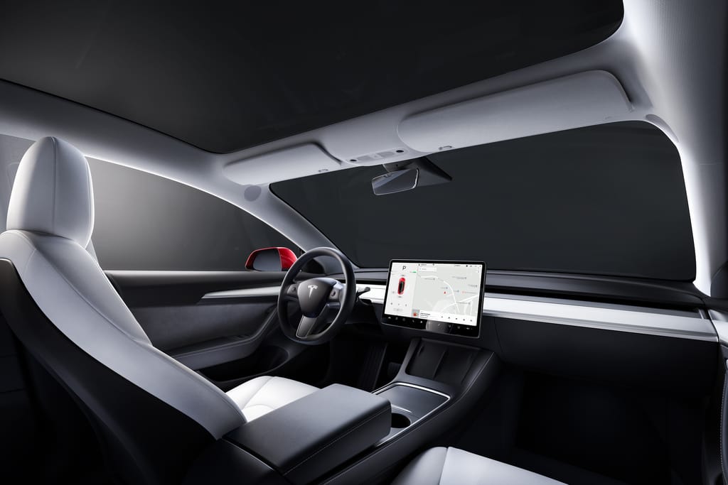 A view of the interior of a Tesla Model 3 with a white interior from the passenger seat