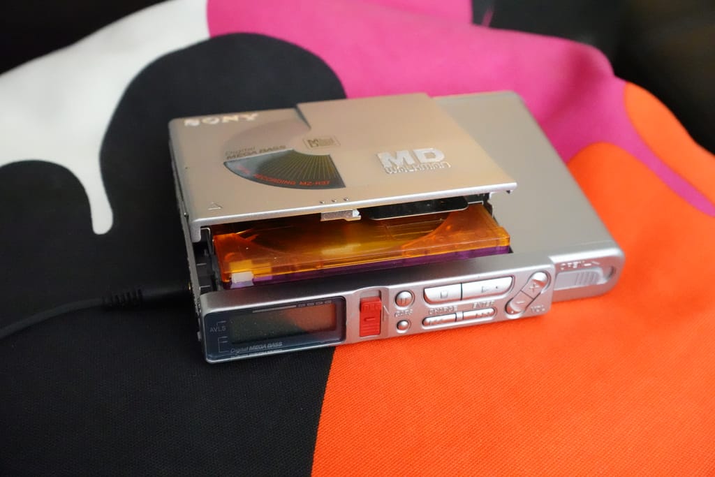 A Sony MZ-R37 MiniDisc player, as seen from the front-top-left corner with a MiniDisc slightly ejected