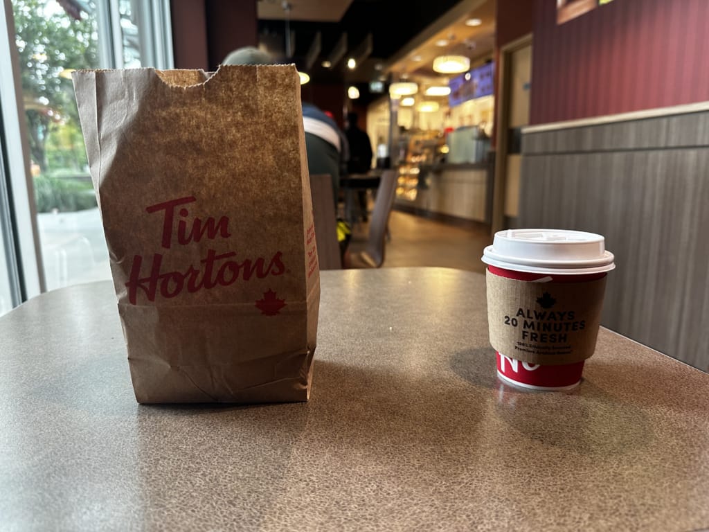 A bag of donuts and a cup of hot chocolate on a table at Tim Horton's